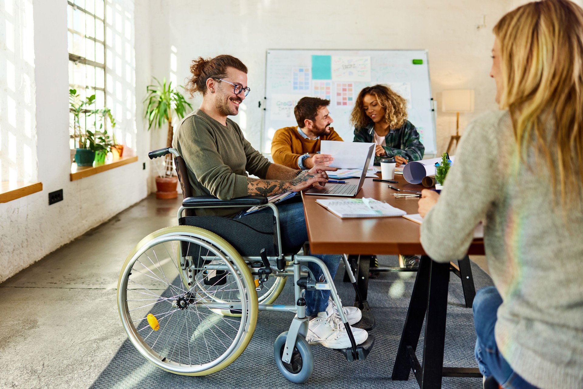 Happy disabled businessman using laptop on a meeting with his colleagues.