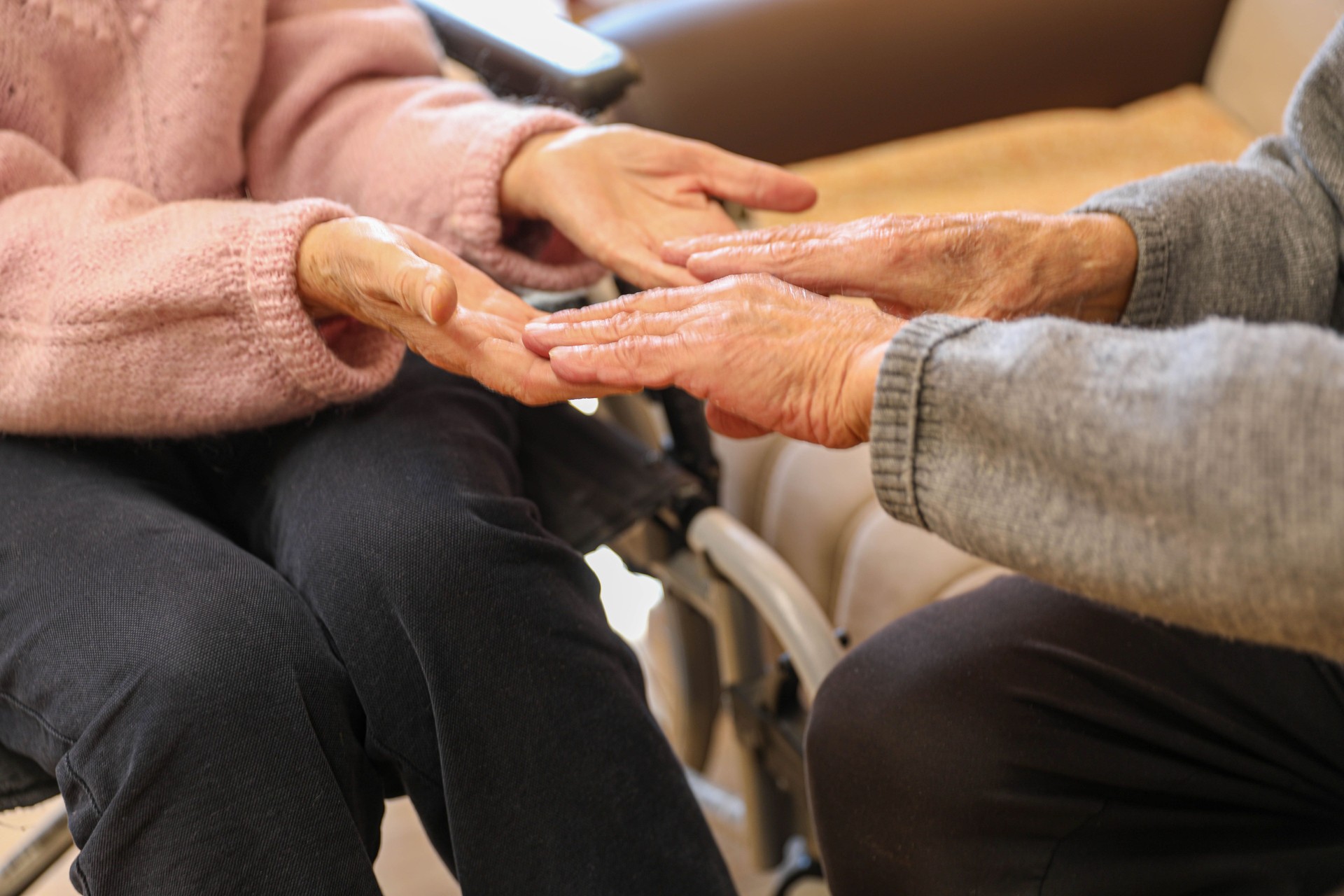 Compassionate Care: A Caregiver Holding an Elderly Woman’s Hands