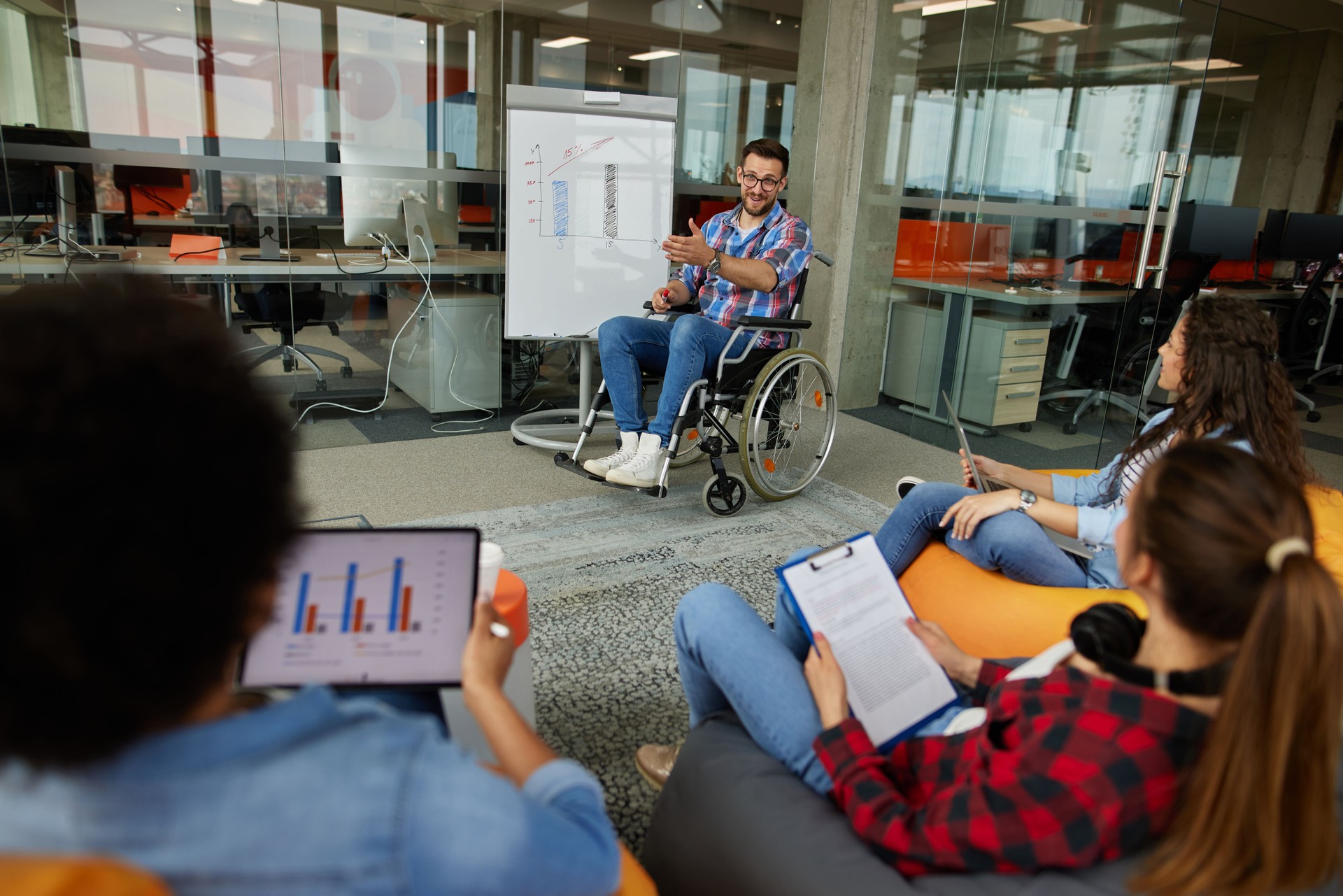Programmer in a wheelchair discussing business moments in a modern office