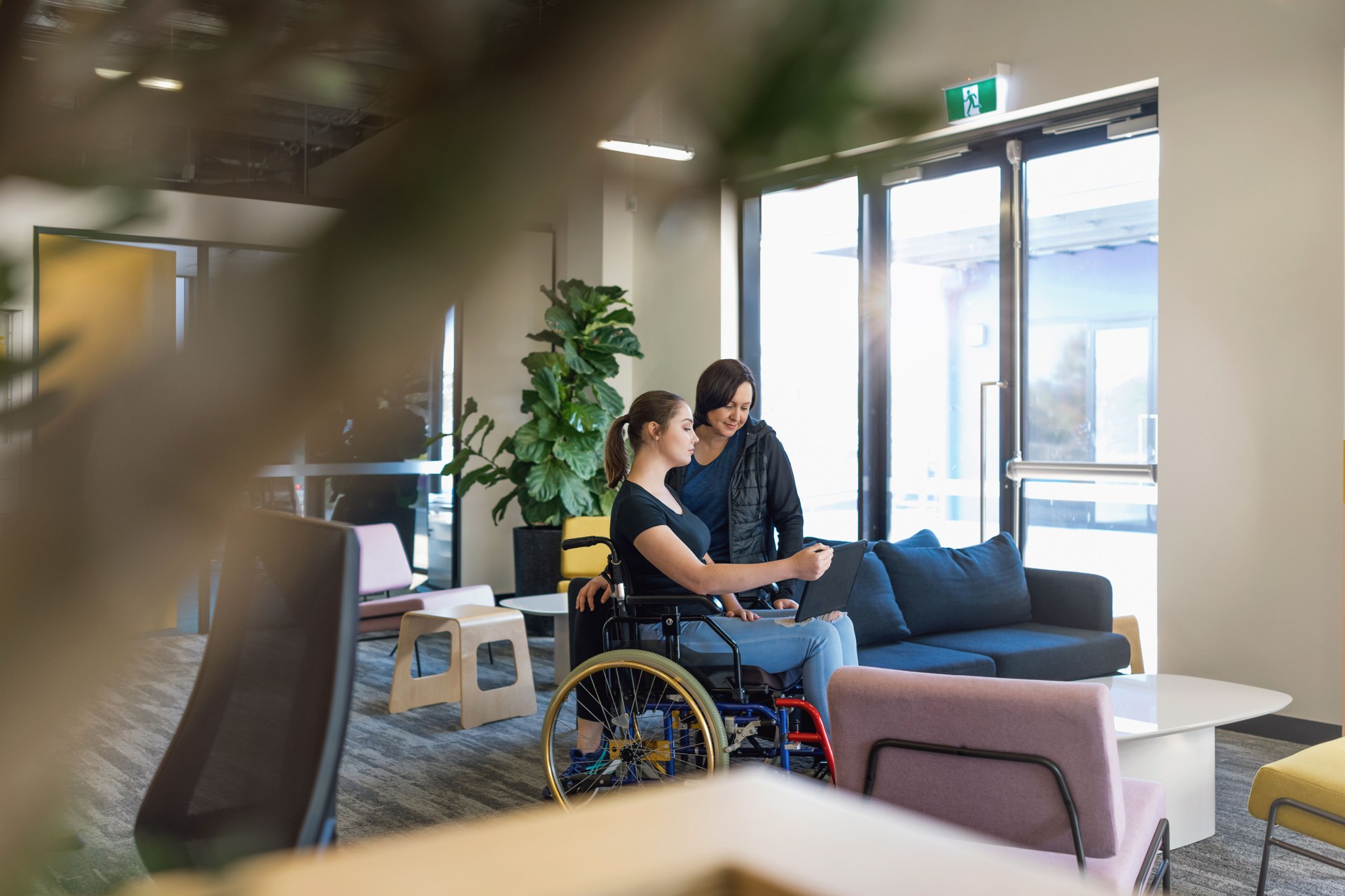 Young Woman In Wheelchair Collaborating With Coworker
